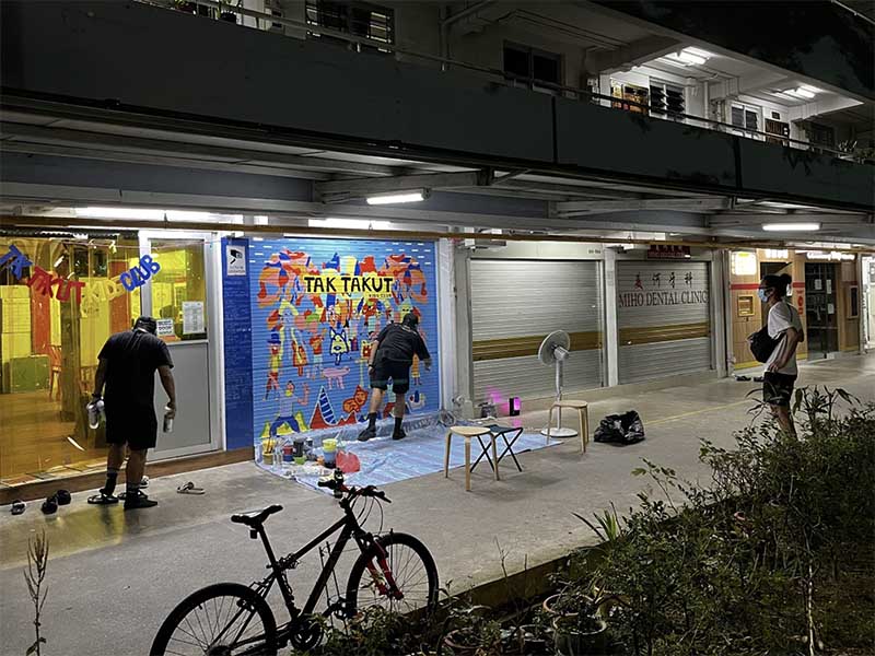 resident in front of mural